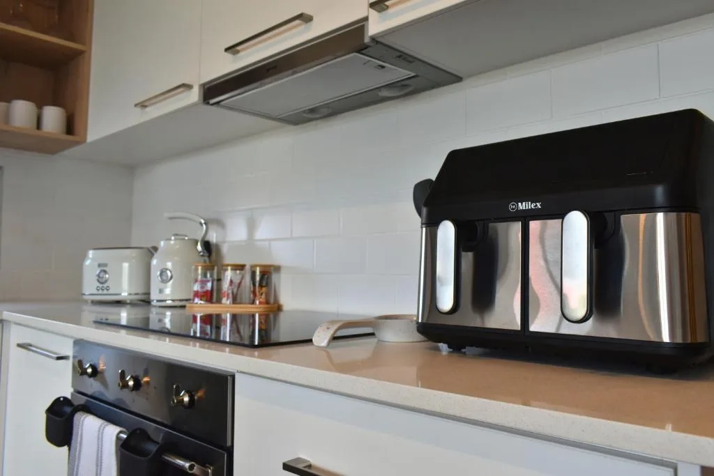 Modern kitchen with white cabinetry, stainless steel appliances, and countertop kettle