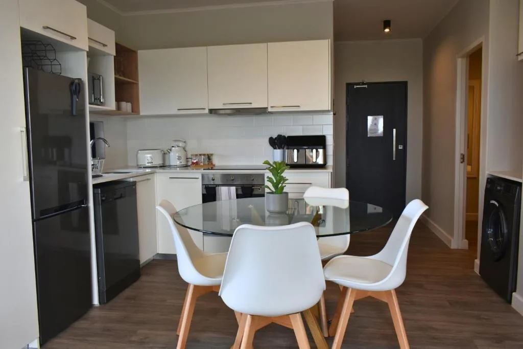 Modern kitchen with white cabinetry, black appliances, and dining table