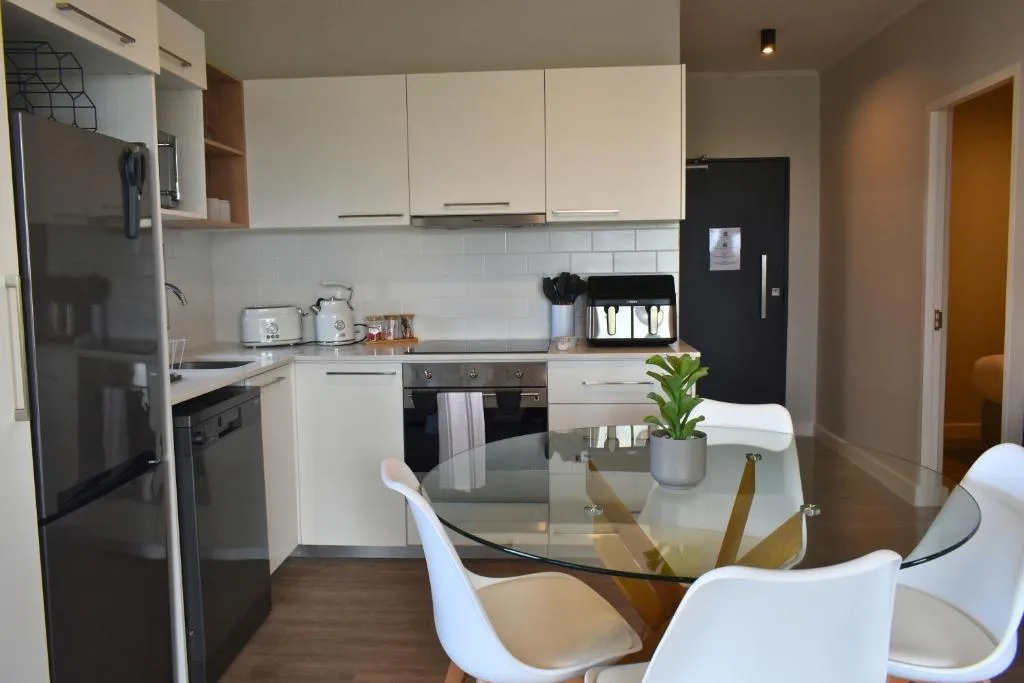 Modern kitchen with white cabinetry, black appliances, and dining area