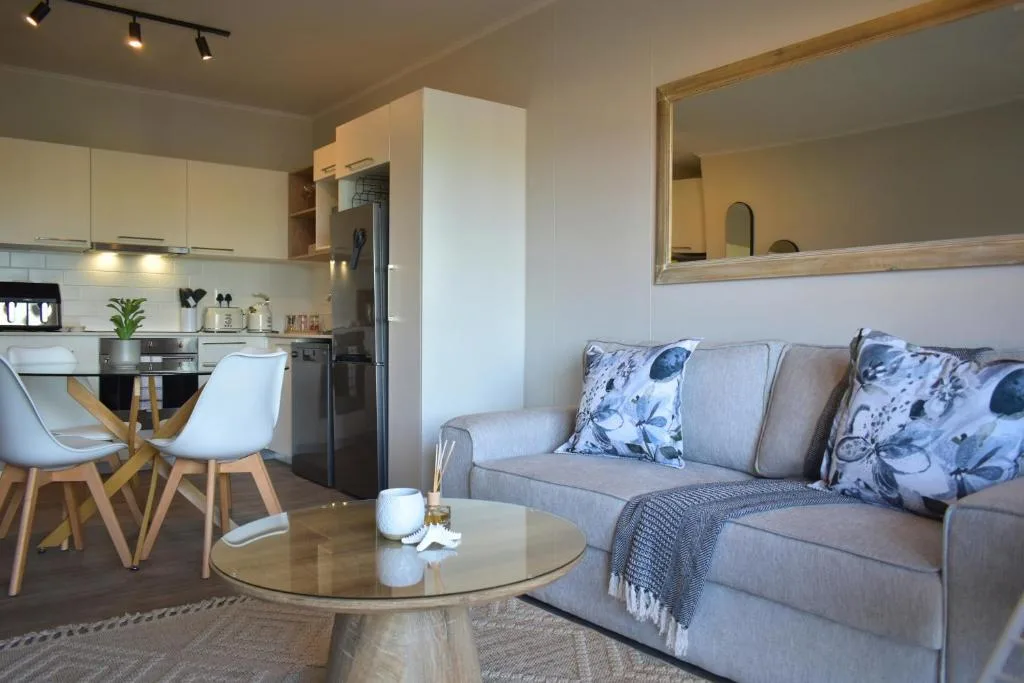 Modern living room with gray sofa, round wooden table, and open-plan kitchen area