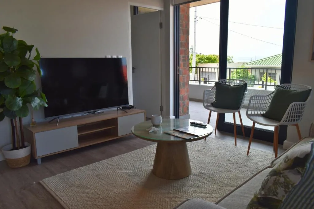 Modern living room with TV, round coffee table, and deck access with mountain views