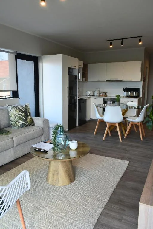 Open-plan lounge with sofa, wooden coffee table, and kitchen beyond