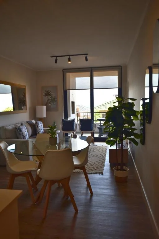 Open-plan lounge with dining area, sofa, and large glass doors overlooking deck