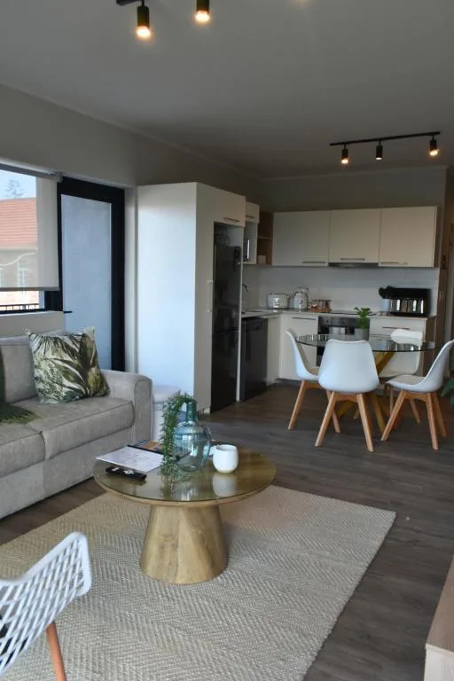 Open-plan lounge and kitchen with sofa, dining table, and modern fixtures
