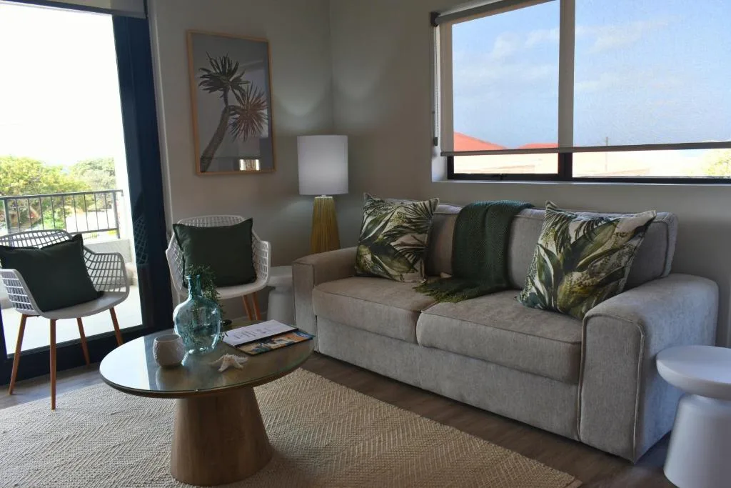Spacious lounge with beige sofa, accent chair, and coastal views through large windows