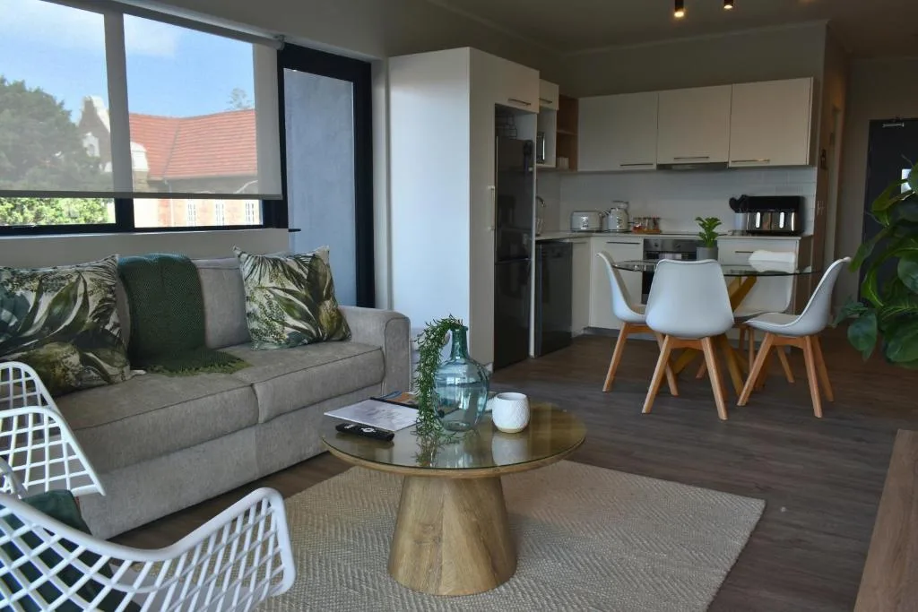Modern lounge with gray sofa, wooden coffee table, and open-plan kitchen view