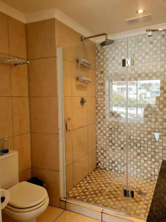 Modern bathroom with large glass shower enclosure and orange tile accents