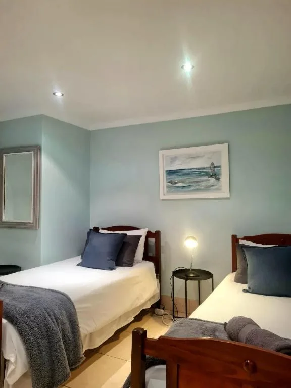 Twin bedroom with wooden beds, soft lighting, and coastal artwork