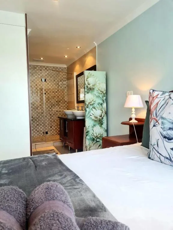 Bedroom with en-suite bathroom, bed, bedside lamp, and turquoise accent wall