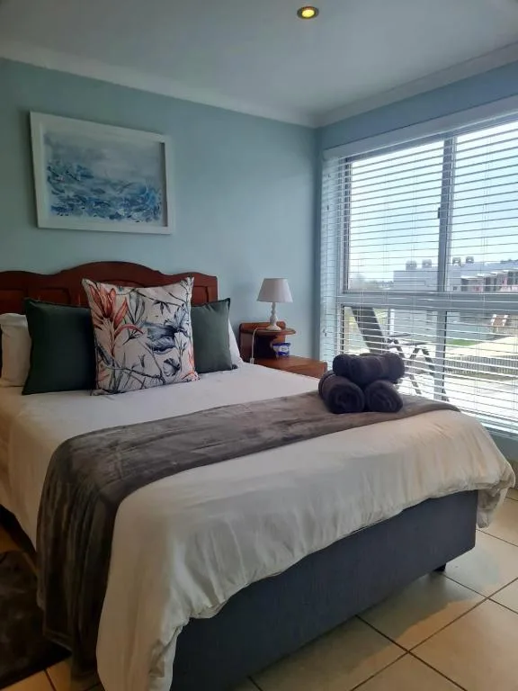 Bright bedroom with queen bed, ocean view windows, and coastal decor