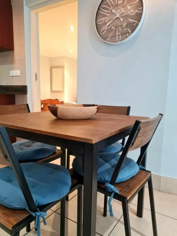 Wooden dining table with blue cushioned chairs and wall clock
