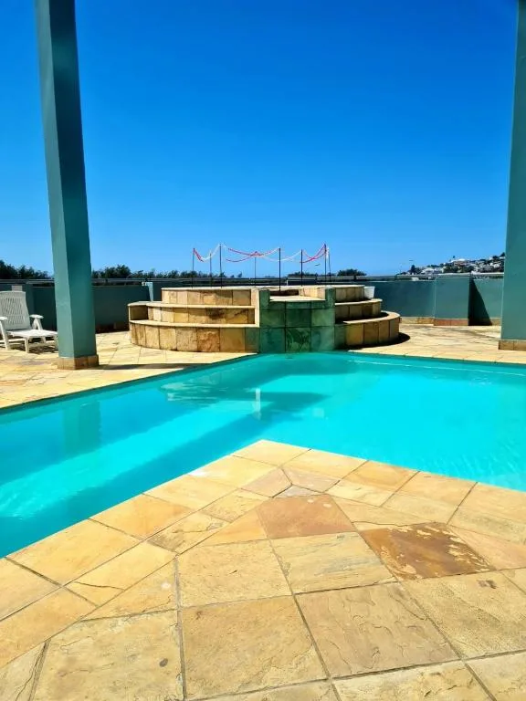 Turquoise swimming pool with flagstone paving and lagoon views beyond