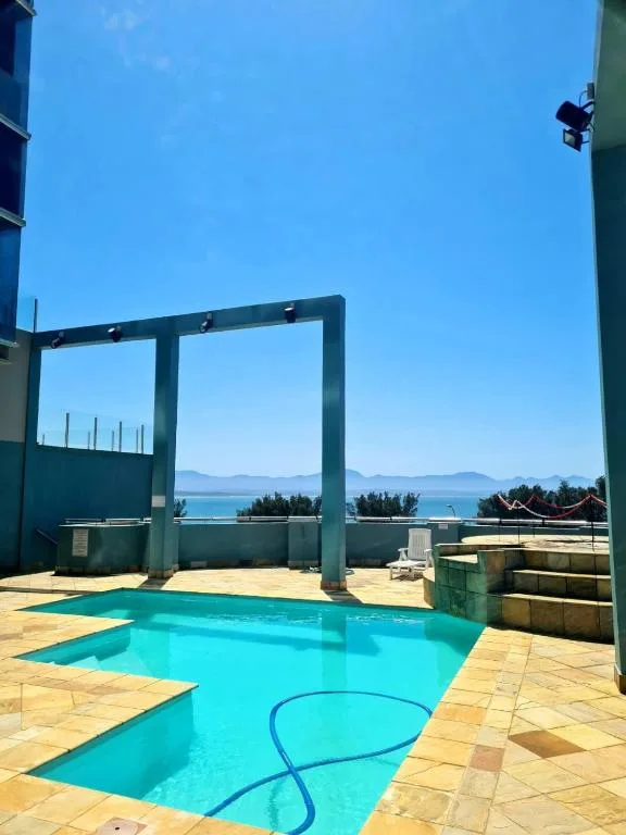Turquoise swimming pool with ocean and mountain views beyond