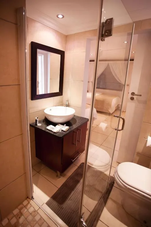 Modern bathroom with round sink vanity, glass shower enclosure, and toilet