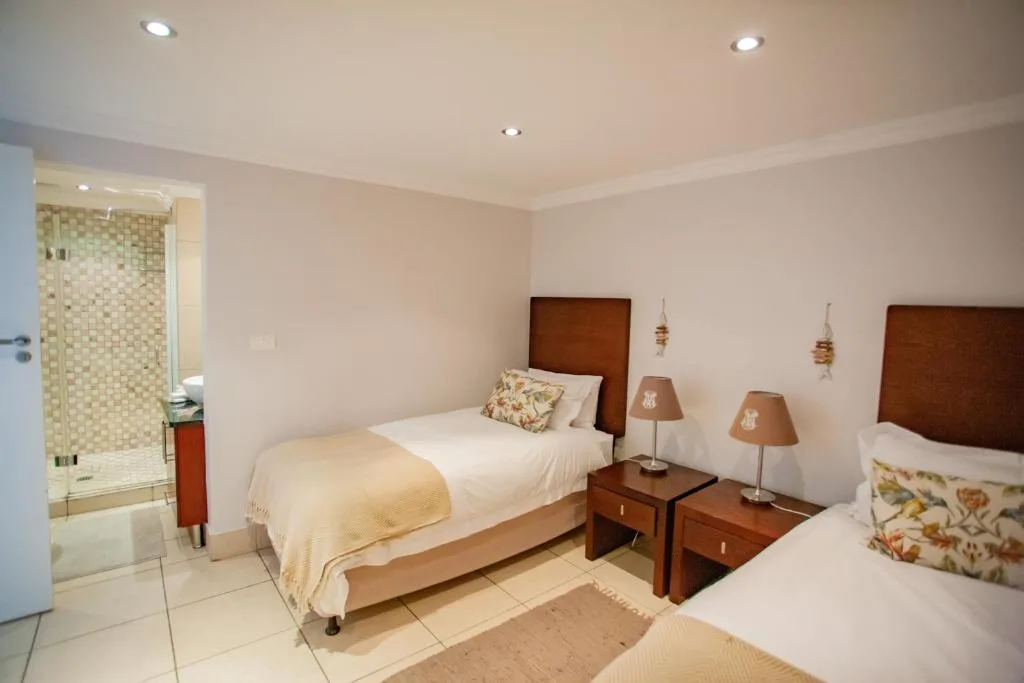 Spacious bedroom with two beds, wooden headboards, and ensuite bathroom