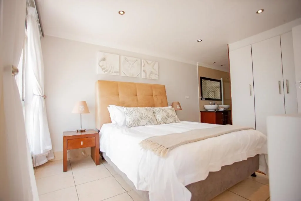 Modern bedroom with orange headboard, white bedding, wooden nightstands