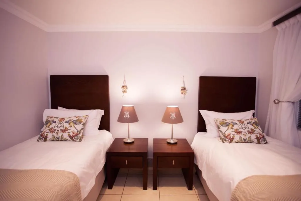 Twin bedroom with dark wooden headboards and matching bedside tables with lamps