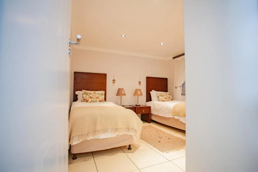 Twin bedroom with wooden headboards, matching lamps, and cream bedding