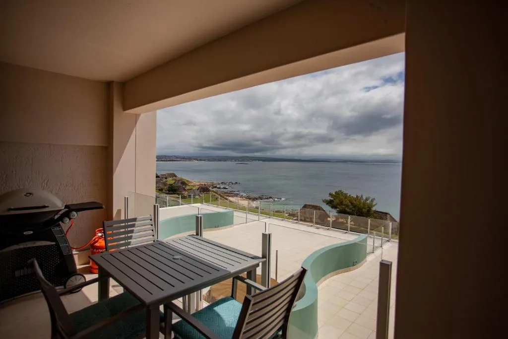 Expansive coastal deck with dining table, braai, and ocean views