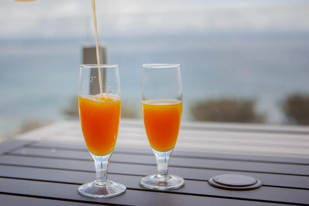 Fresh orange juice drinks served on wooden deck with ocean view