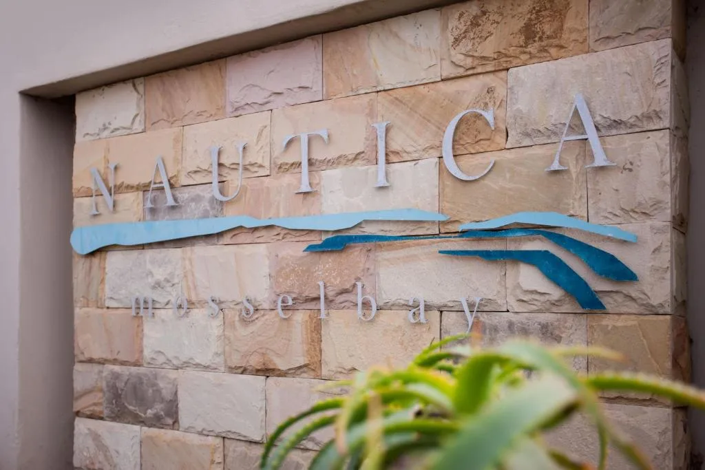 Nautica property signage with blue wave design on stone wall