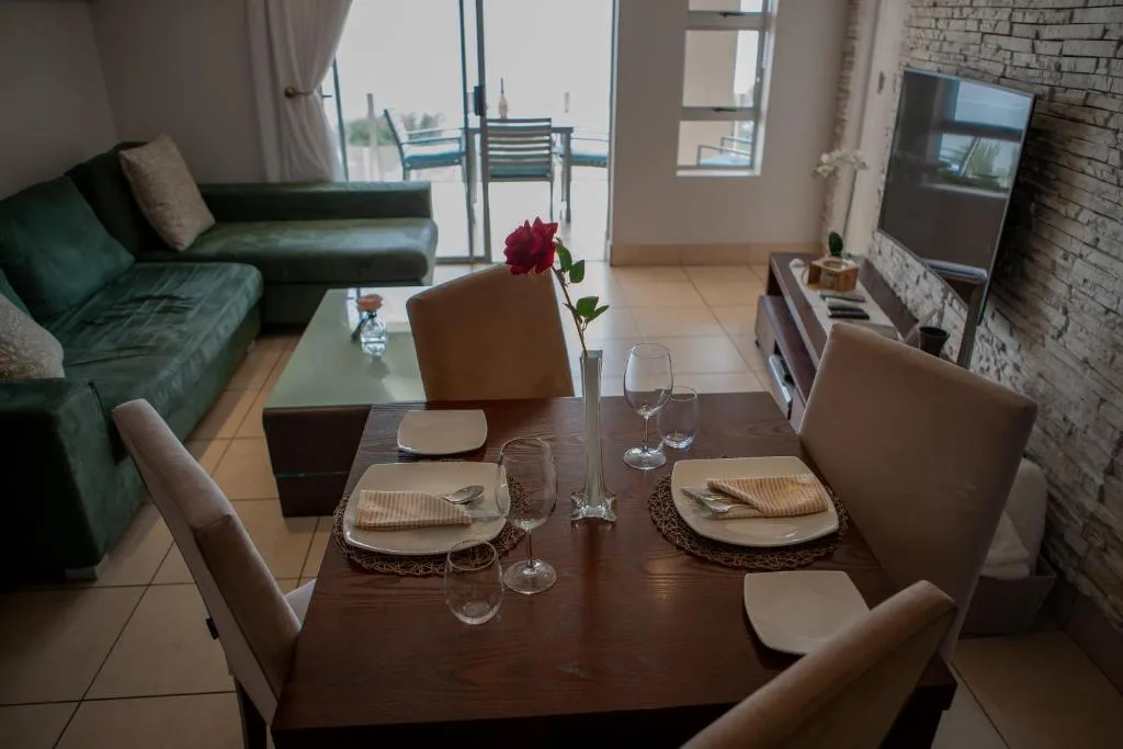 Elegant dining table set for two with red rose centerpiece and ocean view
