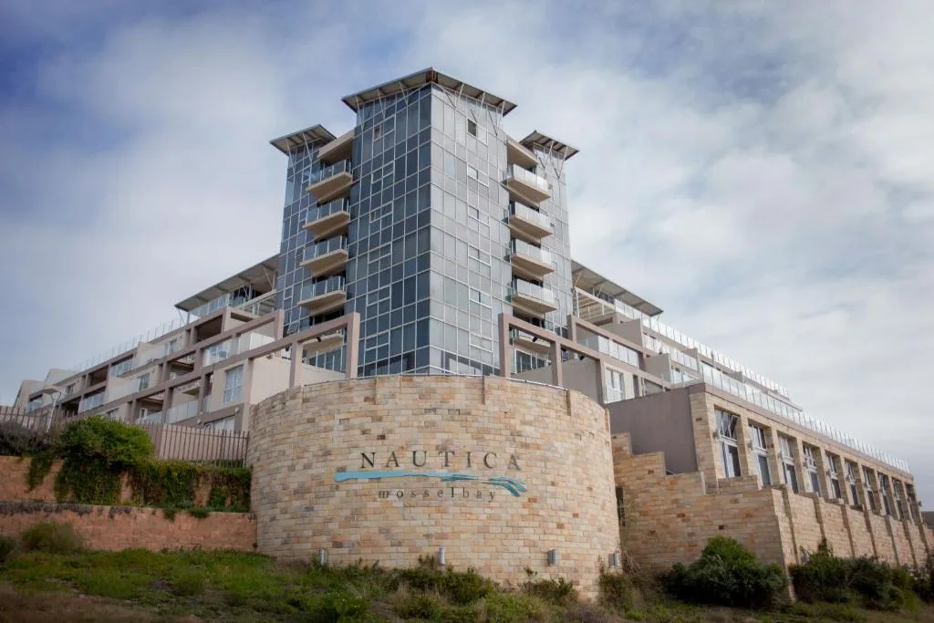 Modern multi-story beachfront apartment building with stone facade and balconies