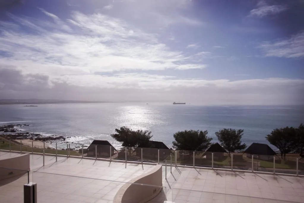Expansive ocean view from seaside deck with calm waters and distant shipping vessel