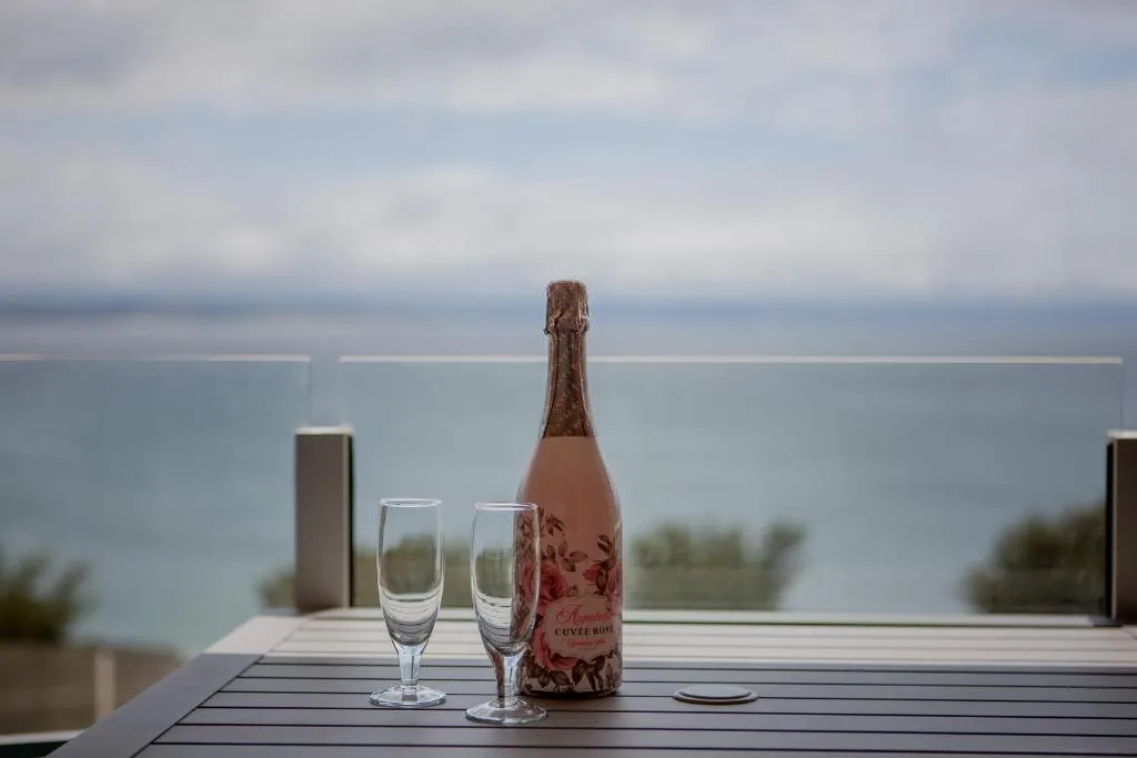 Champagne bottle and glasses on deck overlooking calm lagoon waters