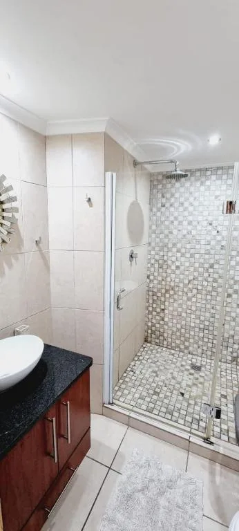 Modern bathroom with walk-in shower, mosaic tiles, and vanity sink