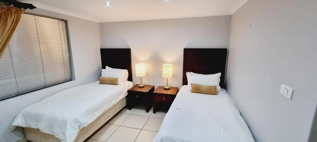 Twin bedroom with dark headboards, bedside lamps, and white linens