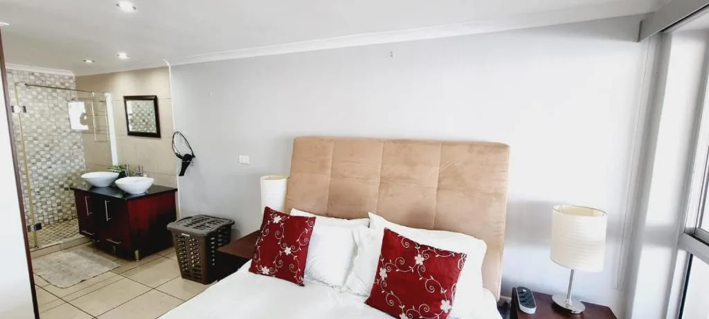 Spacious bedroom with queen bed, en-suite bathroom visible through open door