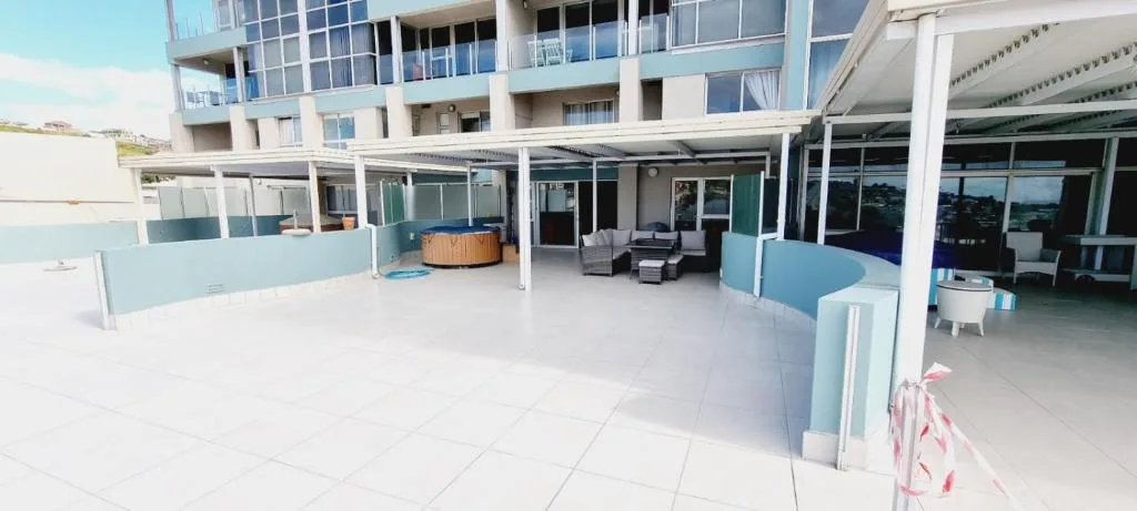 Spacious patio with seating area, hot tub, and ocean views