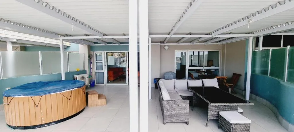 Covered outdoor entertainment area with hot tub and rattan seating furniture