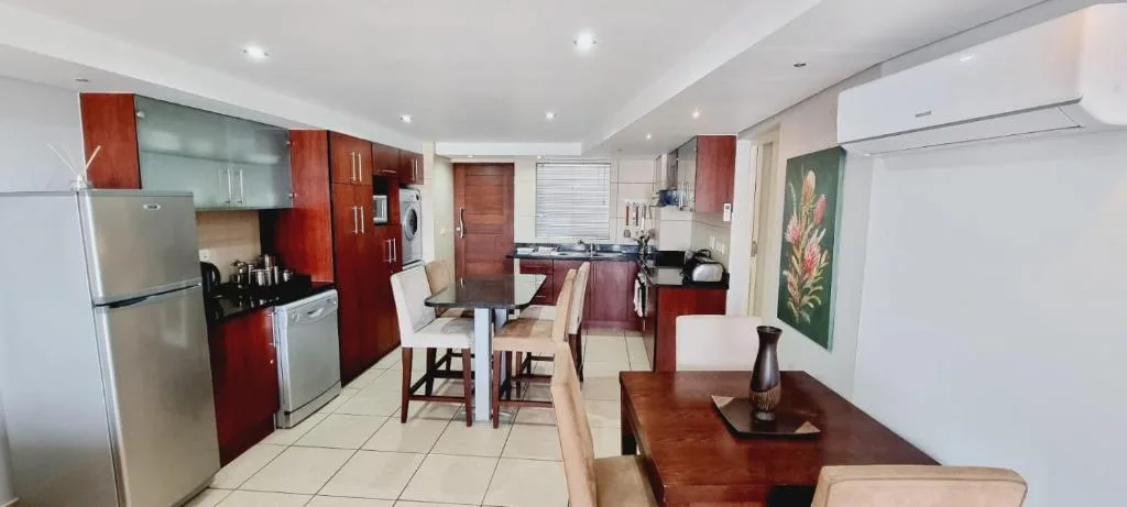 Modern kitchen with red cabinetry, stainless steel appliances, and dining area