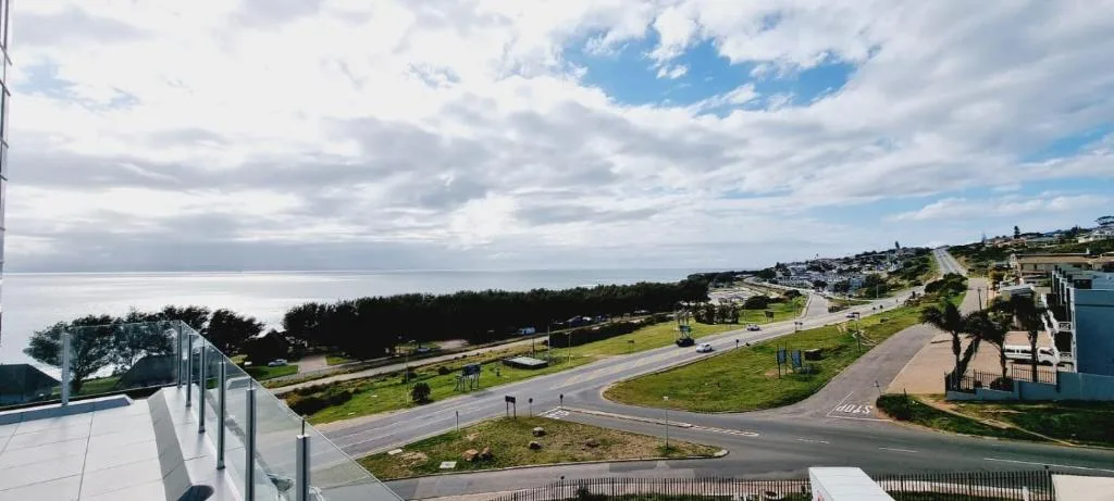 Coastal town vista with ocean, green spaces, and residential buildings visible
