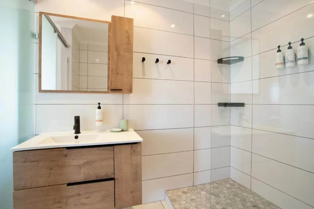 Modern bathroom with wooden vanity, mirror cabinet, and walk-in shower