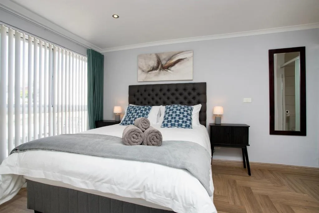 Modern bedroom with queen bed, black headboard, and coastal decor accents