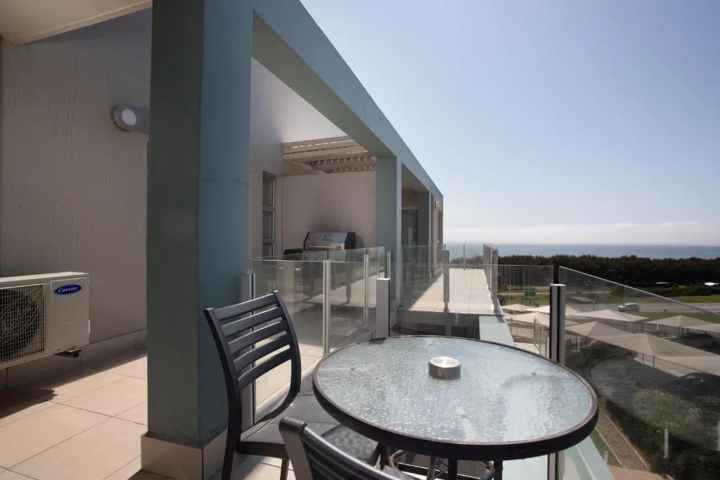 Outdoor patio with dining table overlooking ocean and coastal landscape