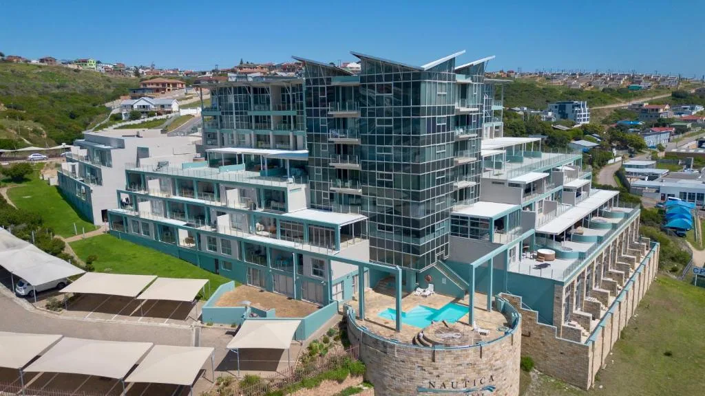 Modern beachfront apartment building with turquoise and white facade overlooking ocean