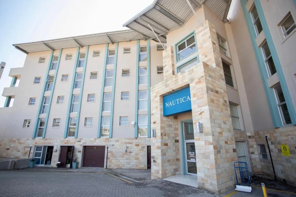 Modern multi-story apartment building facade with turquoise accents and stone entrance