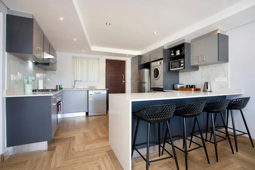 Modern kitchen with gray cabinetry, stainless steel appliances, and breakfast bar seating