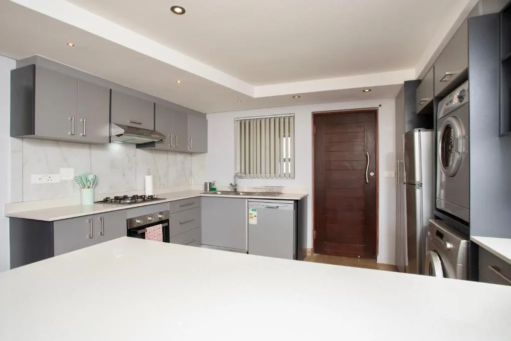 Modern kitchen with gray cabinetry, stainless steel appliances, and white countertops