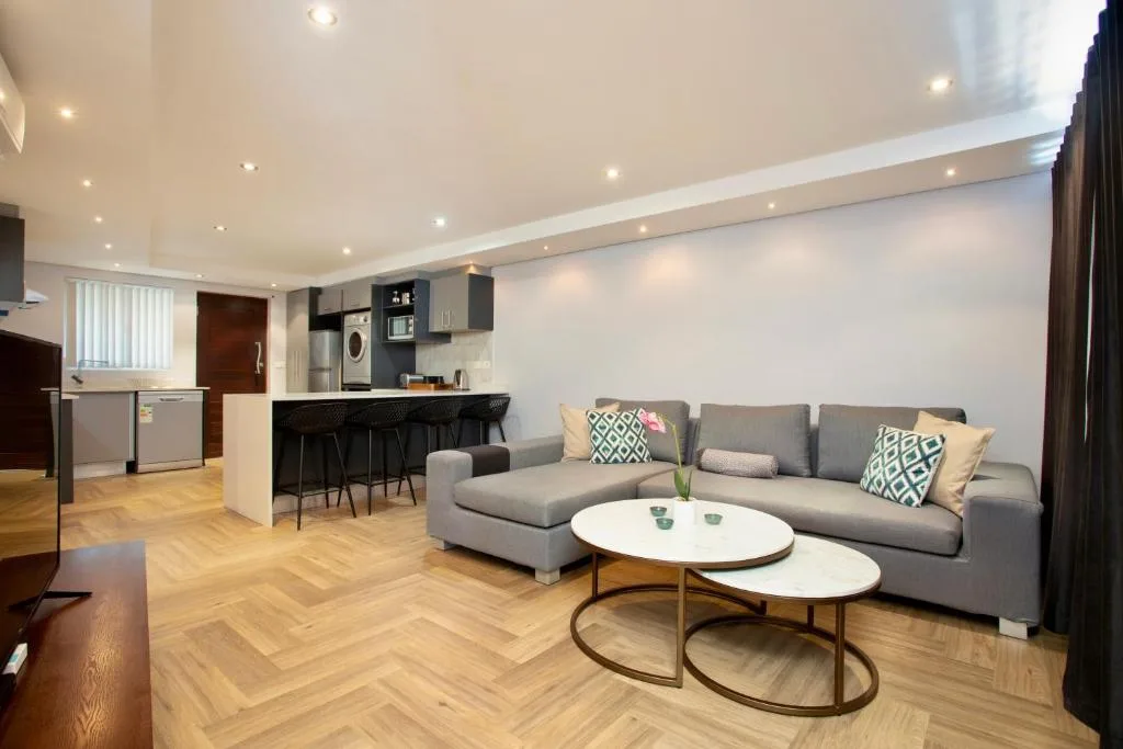 Modern lounge with gray sofa, white coffee table, and kitchen area visible