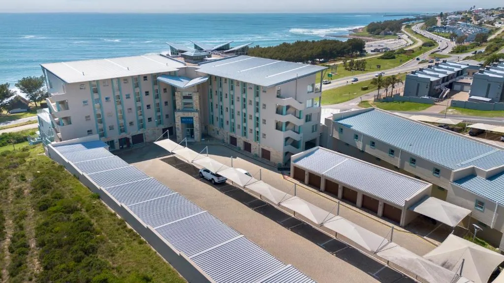 Oceanfront apartment complex with turquoise sea and coastal town beyond