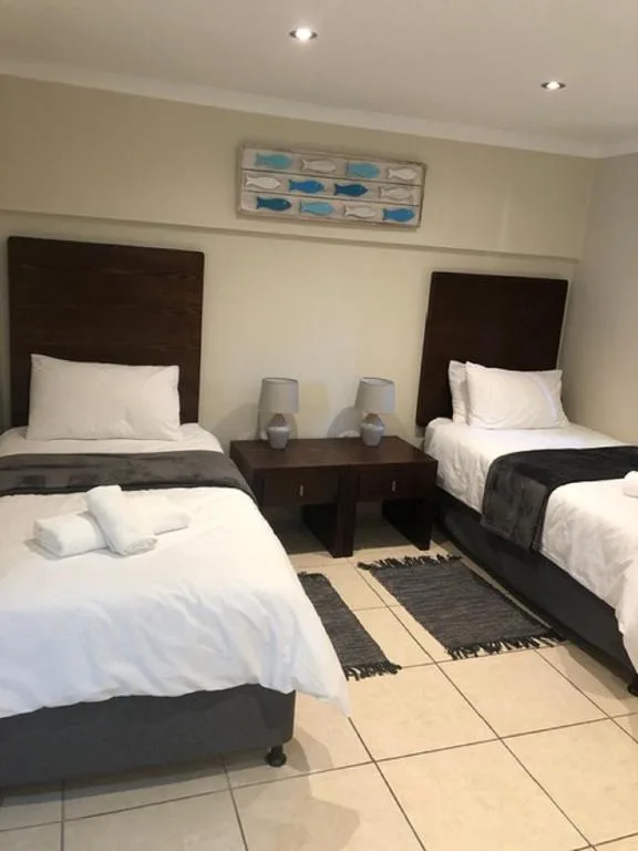Twin bedroom with dark headboards, white linens, and shared nightstand