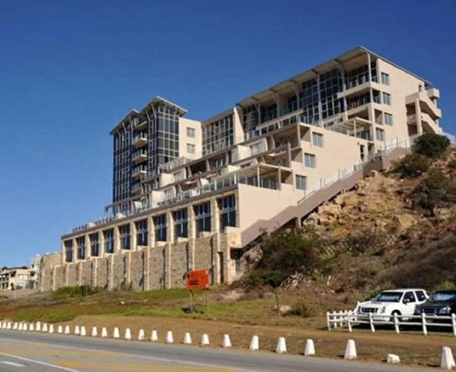 Multi-story beachfront apartment building with modern architecture and parking area