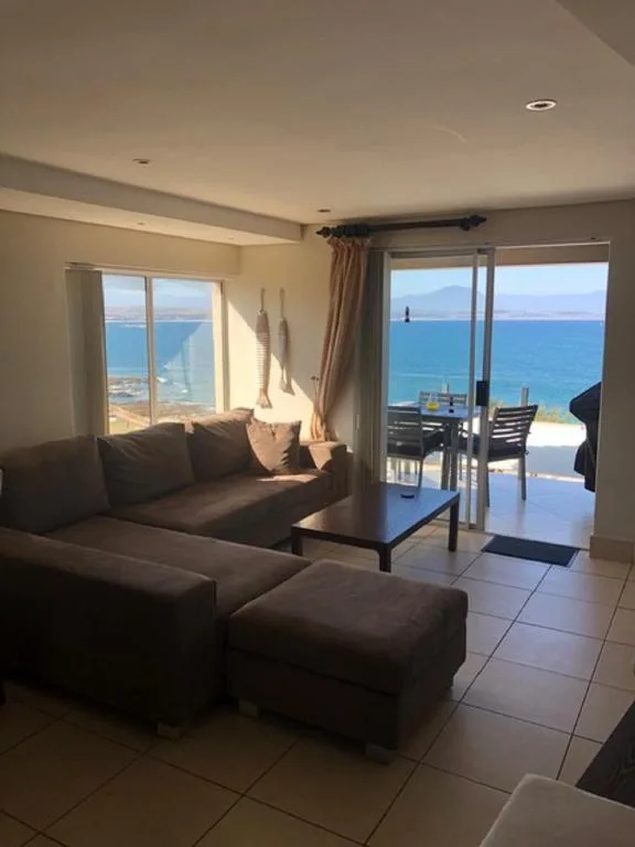 Modern lounge with dark sofa, ocean views through glass doors and windows