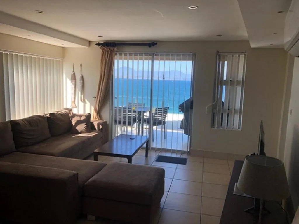 Spacious lounge with dark sofa, ocean view through glass doors, modern lighting