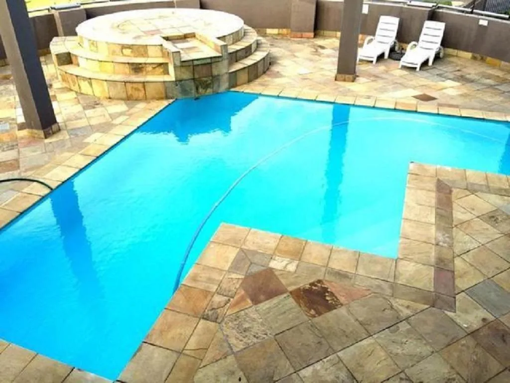 Bright blue swimming pool with tiled surrounds and lounge chairs